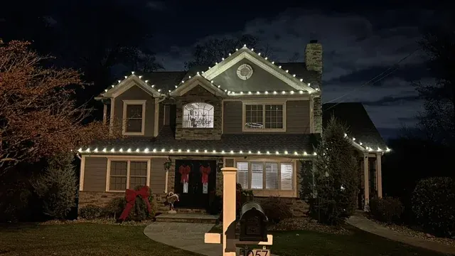 Front view of a Mountainside home with warm white lights along its roof peaks